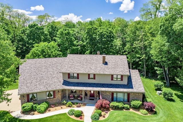 view of front facade featuring brick siding, roof with shingles, and a front yard