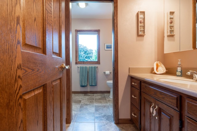 bathroom with baseboards, toilet, and vanity