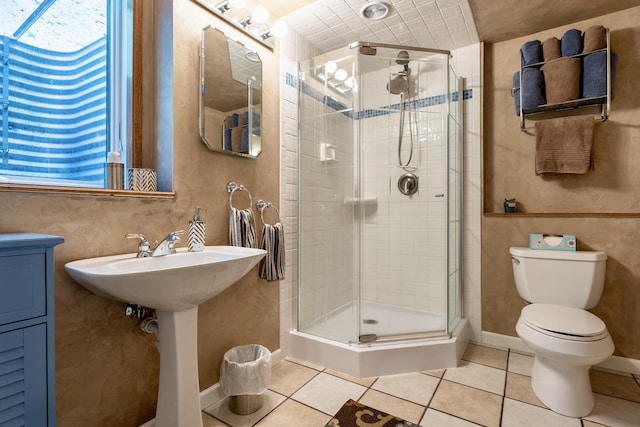 full bath featuring tile patterned floors, baseboards, toilet, and a shower stall