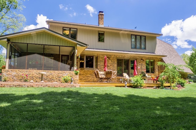 back of house with a yard, brick siding, a sunroom, and a chimney