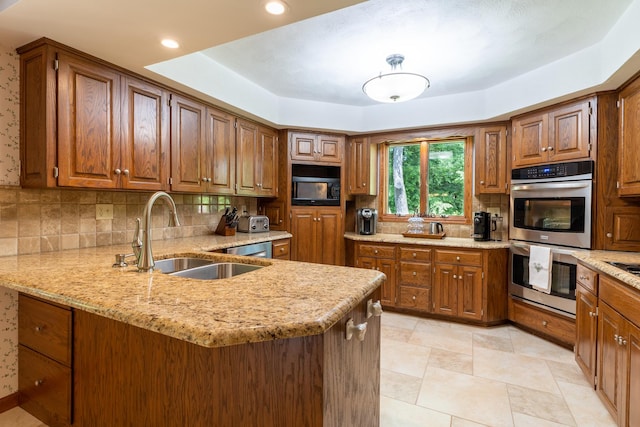 kitchen featuring a sink, double oven, brown cabinetry, black microwave, and decorative backsplash