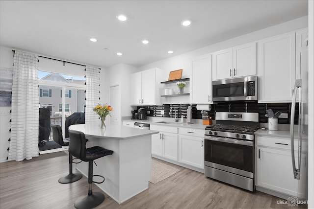 kitchen featuring open shelves, a sink, stainless steel appliances, light countertops, and backsplash