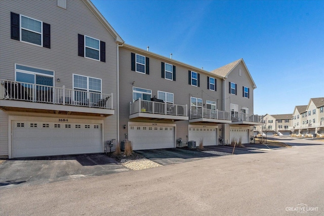 exterior space featuring driveway, central AC unit, a residential view, and a garage