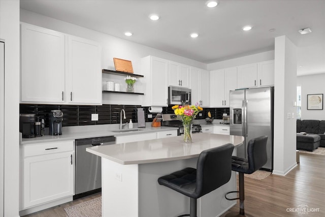kitchen with decorative backsplash, a breakfast bar, appliances with stainless steel finishes, a sink, and white cabinetry
