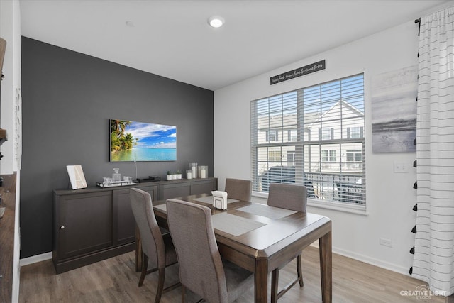 dining room featuring light wood finished floors and baseboards
