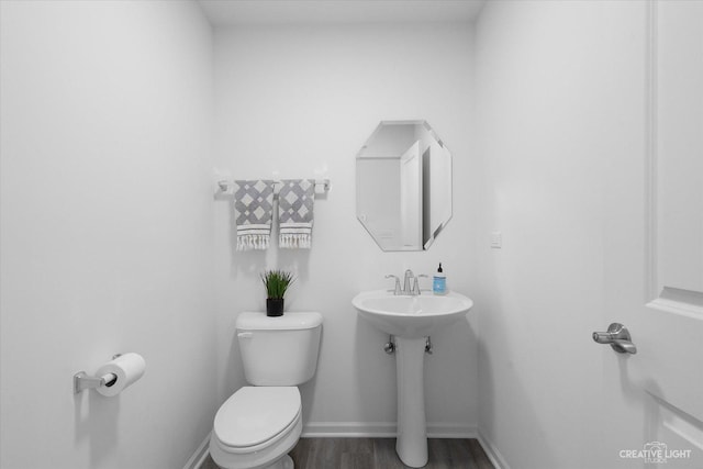 bathroom featuring toilet, wood finished floors, and baseboards