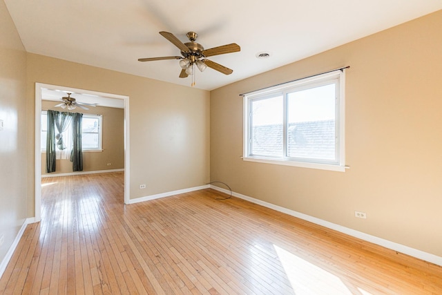 empty room featuring a ceiling fan, baseboards, and light wood-type flooring
