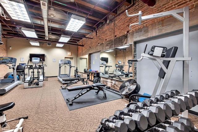 gym with brick wall, carpet, and a towering ceiling