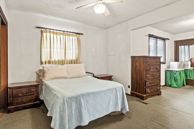 bedroom with a ceiling fan, carpet, visible vents, and a textured ceiling