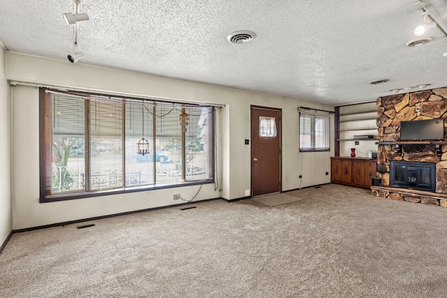 unfurnished living room featuring carpet floors, baseboards, visible vents, and a stone fireplace