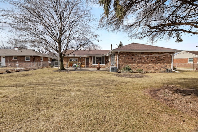 rear view of house with brick siding, a yard, fence, and central air condition unit