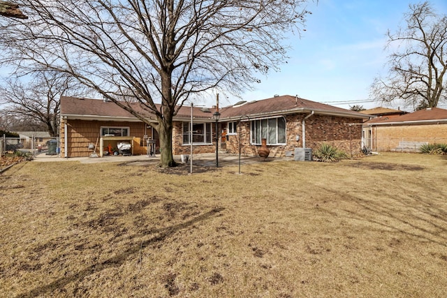 view of front facade featuring a front lawn, central AC unit, fence, and brick siding