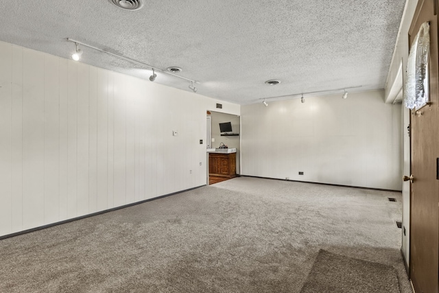 empty room featuring carpet floors, track lighting, visible vents, and a textured ceiling