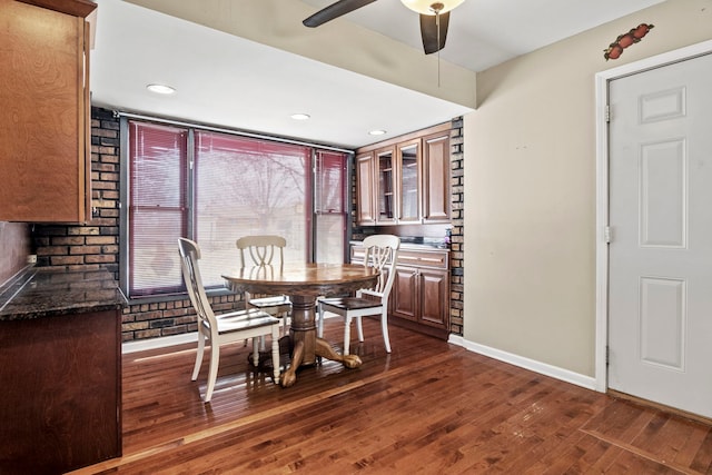 dining area featuring a ceiling fan, baseboards, and dark wood-type flooring