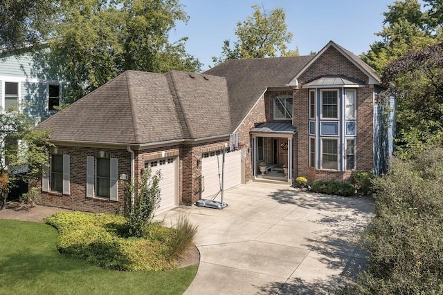 traditional-style home with a garage, brick siding, driveway, and a shingled roof