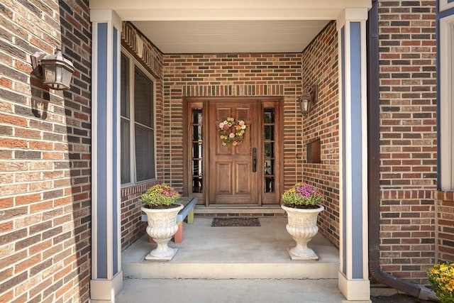 doorway to property featuring brick siding and covered porch