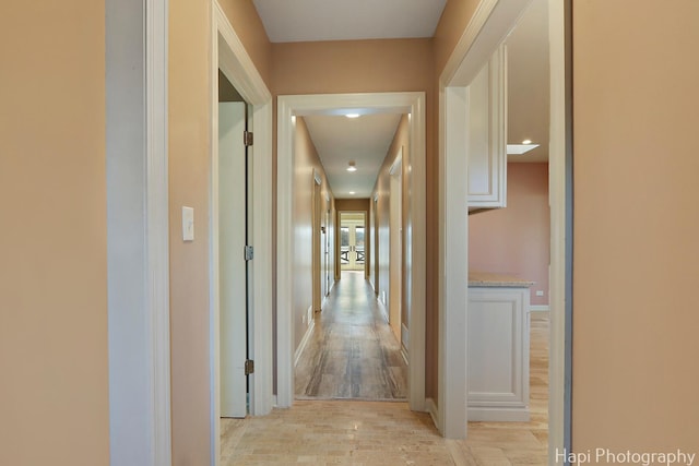 hallway featuring baseboards and light wood-type flooring