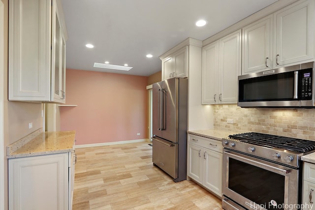 kitchen with light wood finished floors, light stone counters, decorative backsplash, recessed lighting, and stainless steel appliances