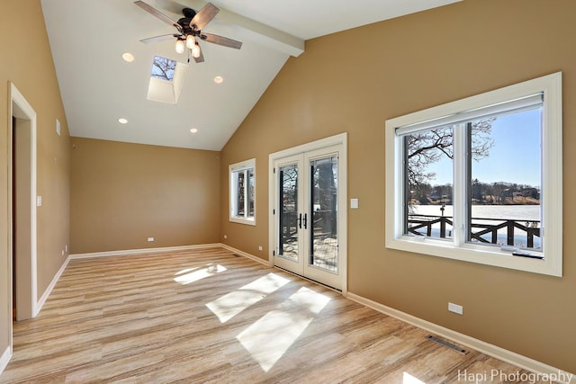 spare room with beam ceiling, high vaulted ceiling, french doors, light wood finished floors, and baseboards