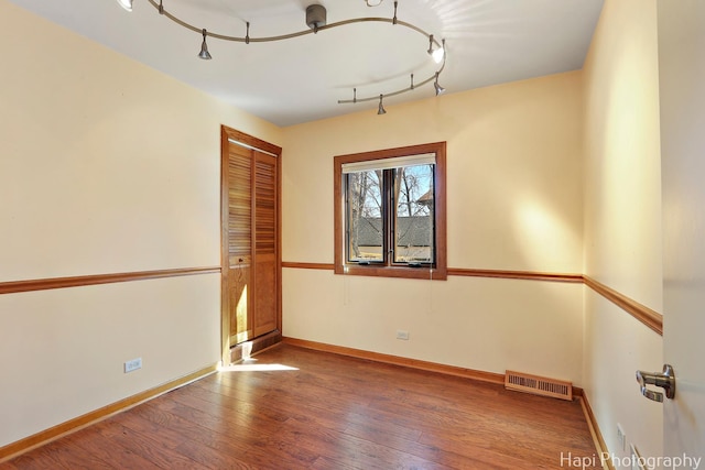 spare room with hardwood / wood-style flooring, baseboards, and visible vents