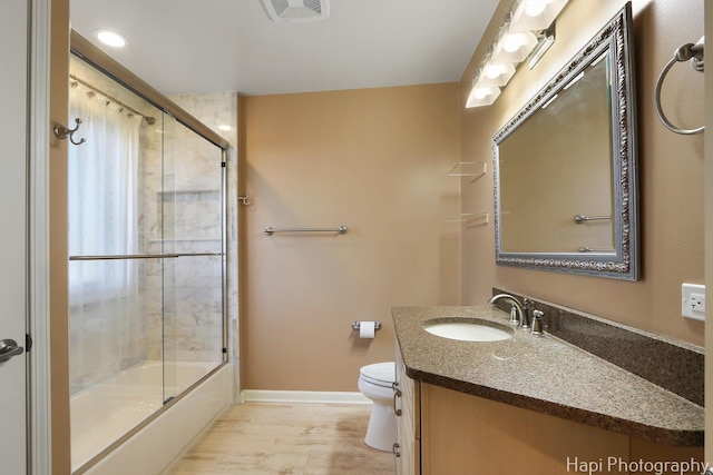 bathroom featuring visible vents, baseboards, toilet, shower / bath combination with glass door, and vanity