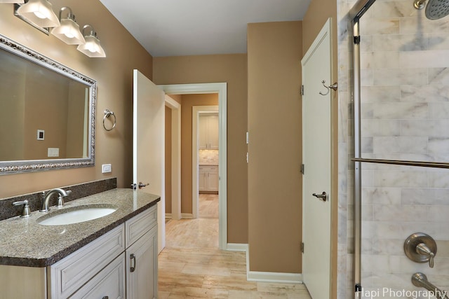 bathroom featuring vanity, baseboards, and a tile shower