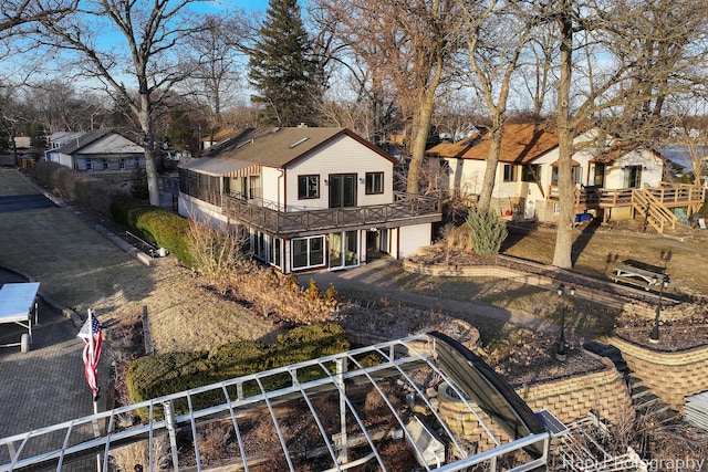 back of house featuring a residential view, a balcony, dirt driveway, and fence