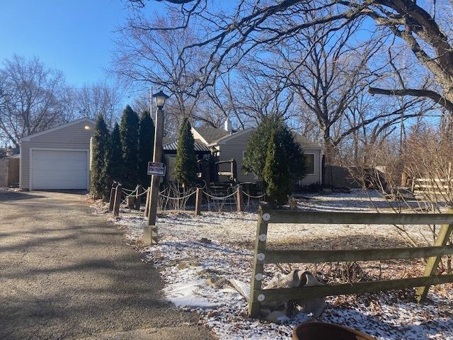 view of side of home featuring an outbuilding, a detached garage, and fence