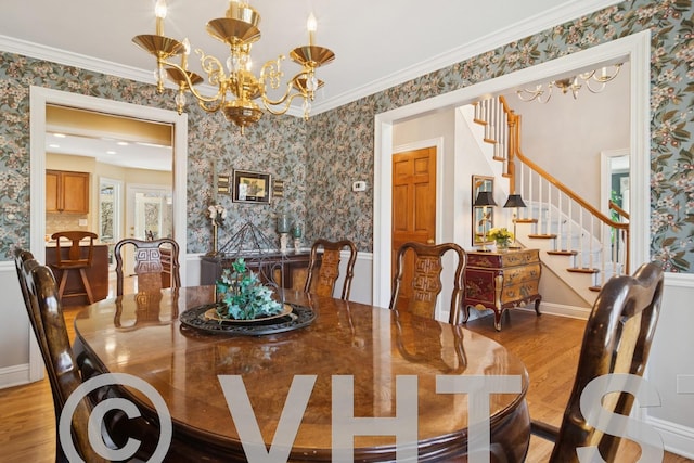 dining room with stairway, an inviting chandelier, wood finished floors, and wallpapered walls