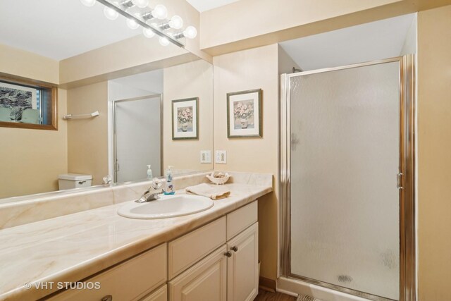 bathroom with toilet, a stall shower, and vanity