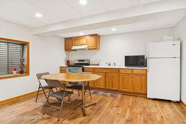 kitchen featuring stainless steel gas range oven, black microwave, under cabinet range hood, freestanding refrigerator, and a sink