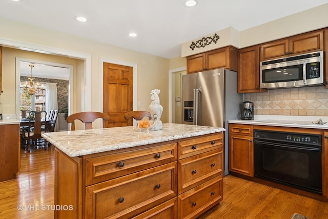 kitchen with brown cabinetry, wood finished floors, and appliances with stainless steel finishes