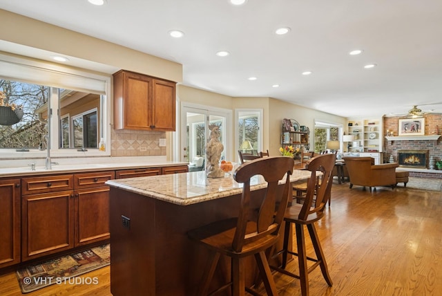 kitchen with a breakfast bar, a sink, dark wood-style floors, a center island, and a brick fireplace