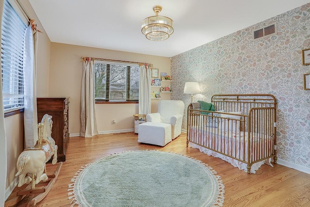 bedroom featuring wallpapered walls, baseboards, visible vents, and wood finished floors