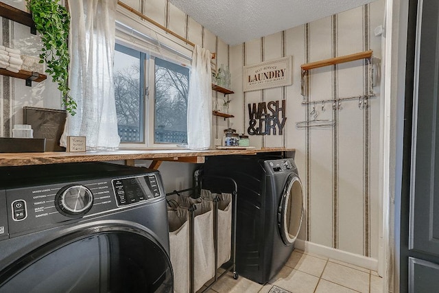 laundry area featuring laundry area, light tile patterned floors, baseboards, a textured ceiling, and washing machine and dryer