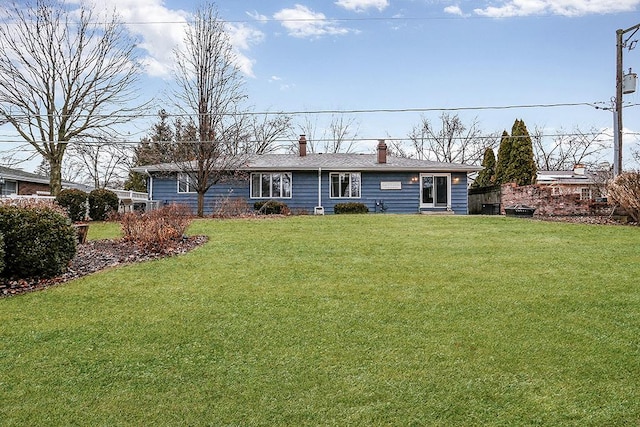 rear view of property with a chimney and a lawn