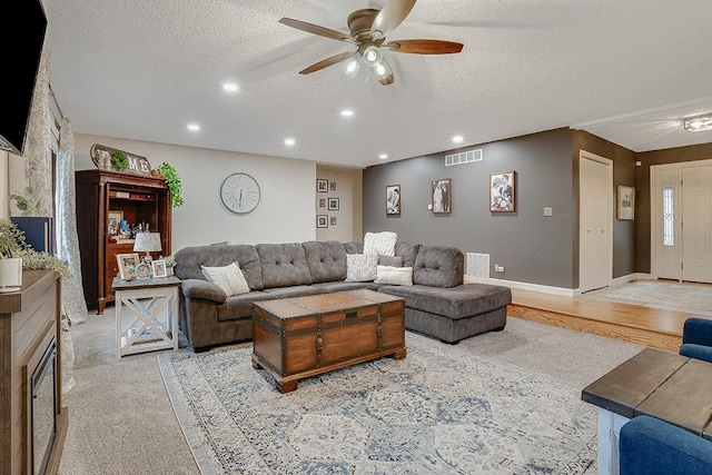 living area featuring recessed lighting, visible vents, a textured ceiling, and baseboards