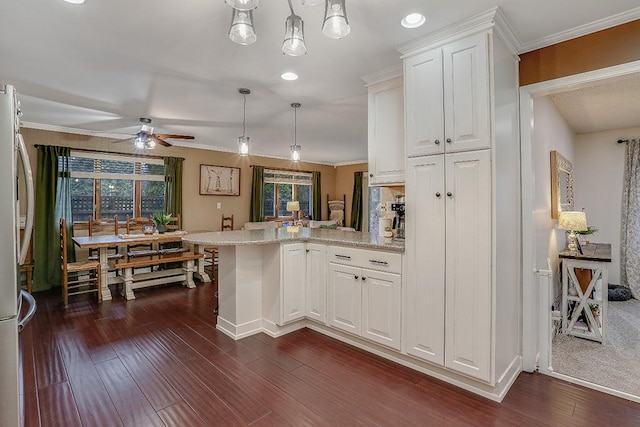 kitchen with white cabinets, ornamental molding, dark wood-type flooring, freestanding refrigerator, and a peninsula