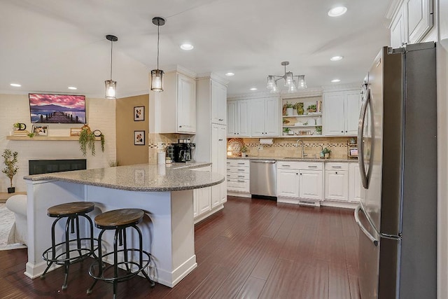 kitchen with a peninsula, white cabinetry, stainless steel appliances, and dark wood-style flooring