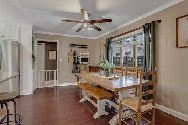 dining space featuring dark wood-style floors, ceiling fan, baseboards, and crown molding