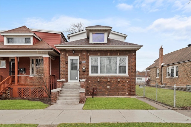 view of front of house with brick siding, a porch, a shingled roof, fence, and a front lawn