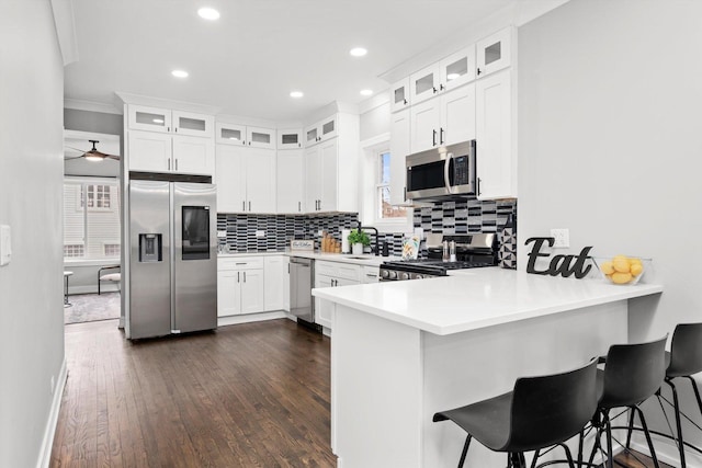 kitchen with stainless steel appliances, a breakfast bar, a peninsula, and decorative backsplash