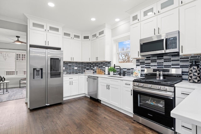 kitchen featuring dark wood-style floors, tasteful backsplash, light countertops, appliances with stainless steel finishes, and a sink