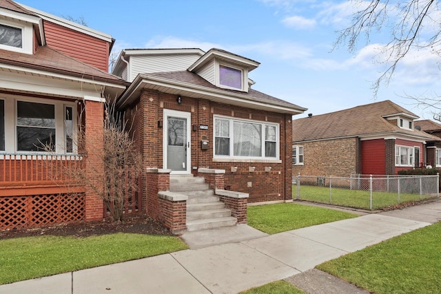 bungalow-style house with brick siding, a front yard, and fence