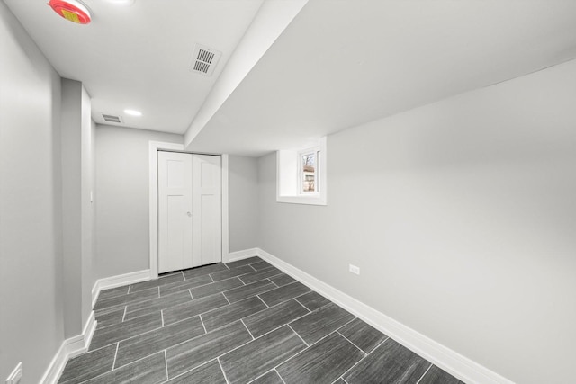 basement with wood tiled floor, visible vents, and baseboards