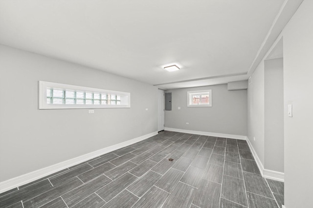 basement featuring wood finish floors, electric panel, and baseboards