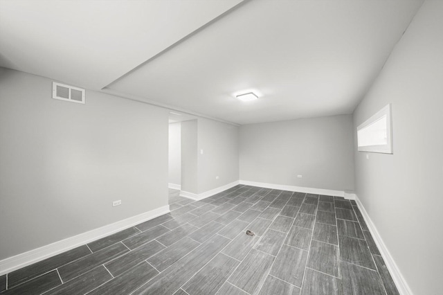 below grade area featuring wood tiled floor, visible vents, and baseboards