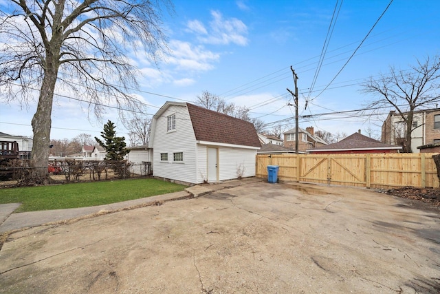 view of property exterior with a shingled roof, a gambrel roof, fence private yard, a gate, and a yard