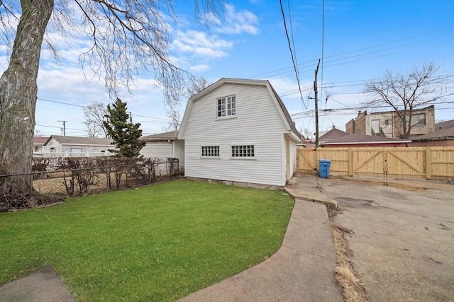 back of house with a gate, a fenced backyard, a lawn, and a gambrel roof