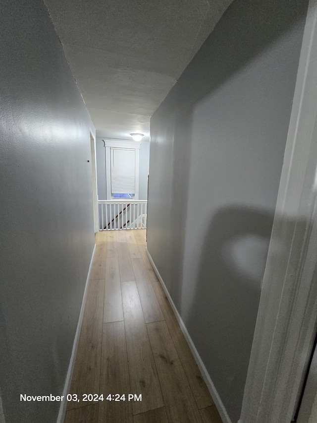 hall featuring wood-type flooring and baseboards